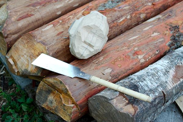 Nyfällda stockar, japansåg och huvudet till en träskulptur