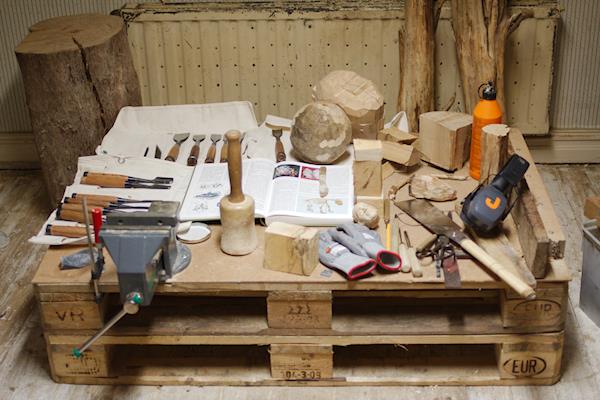 Handverktyg för arbete med träskulptur på en arbetsplattform med mothåll.